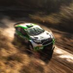 white and green racing car on dirt road